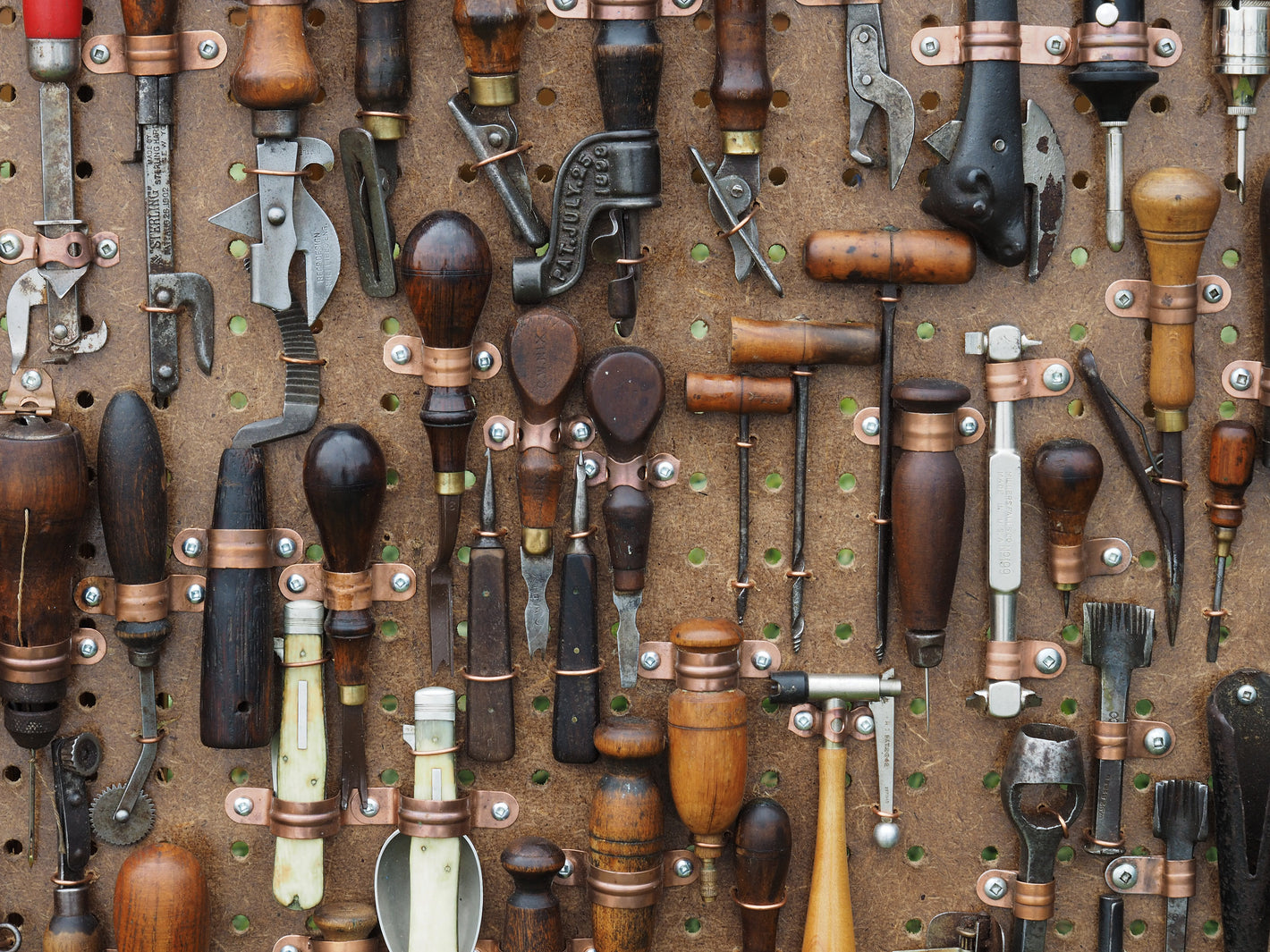 A wall pegboard of various vintage hand tools.